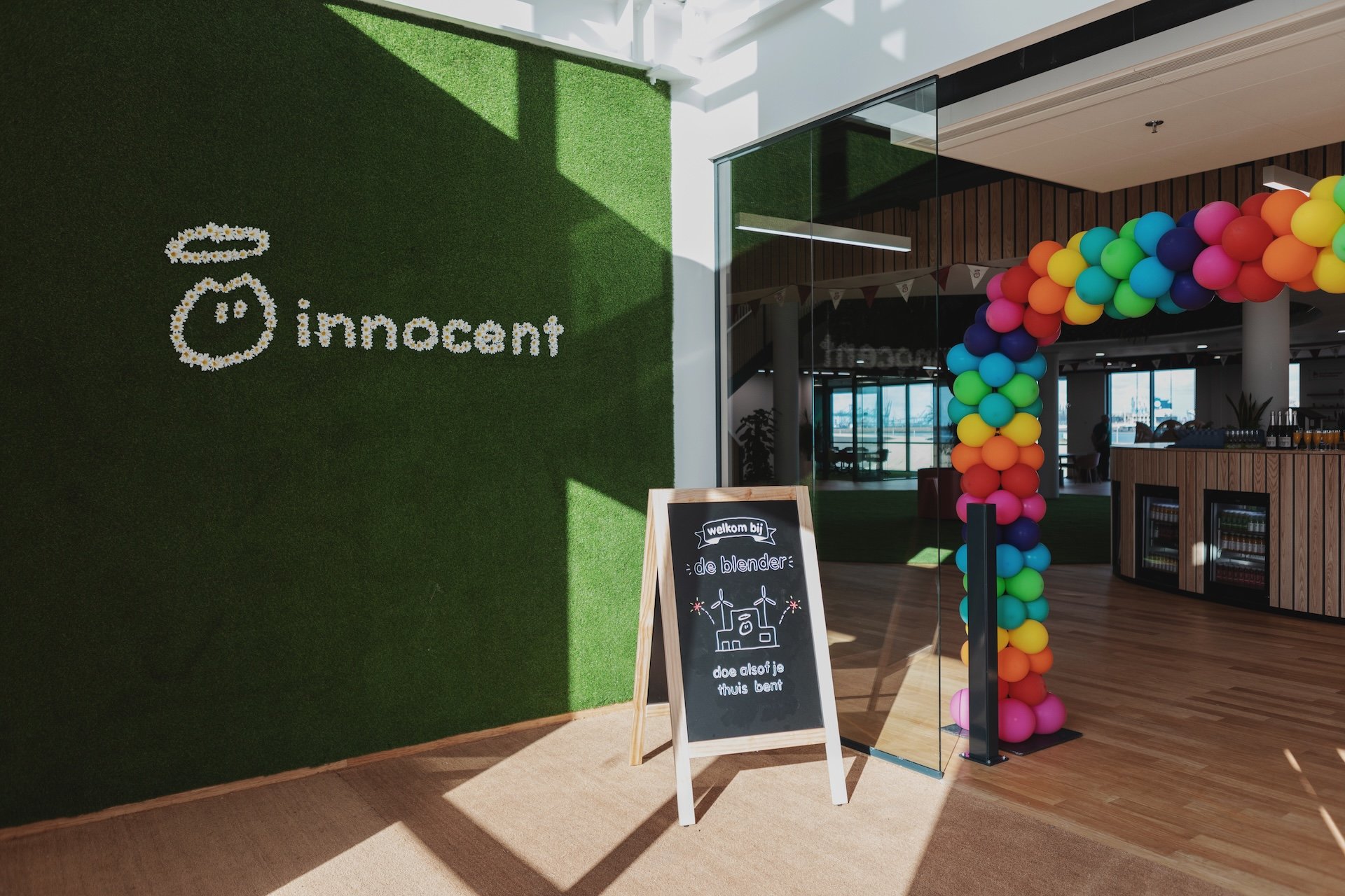 Innocent office entrance with a sign, grass wall, and balloon arch.