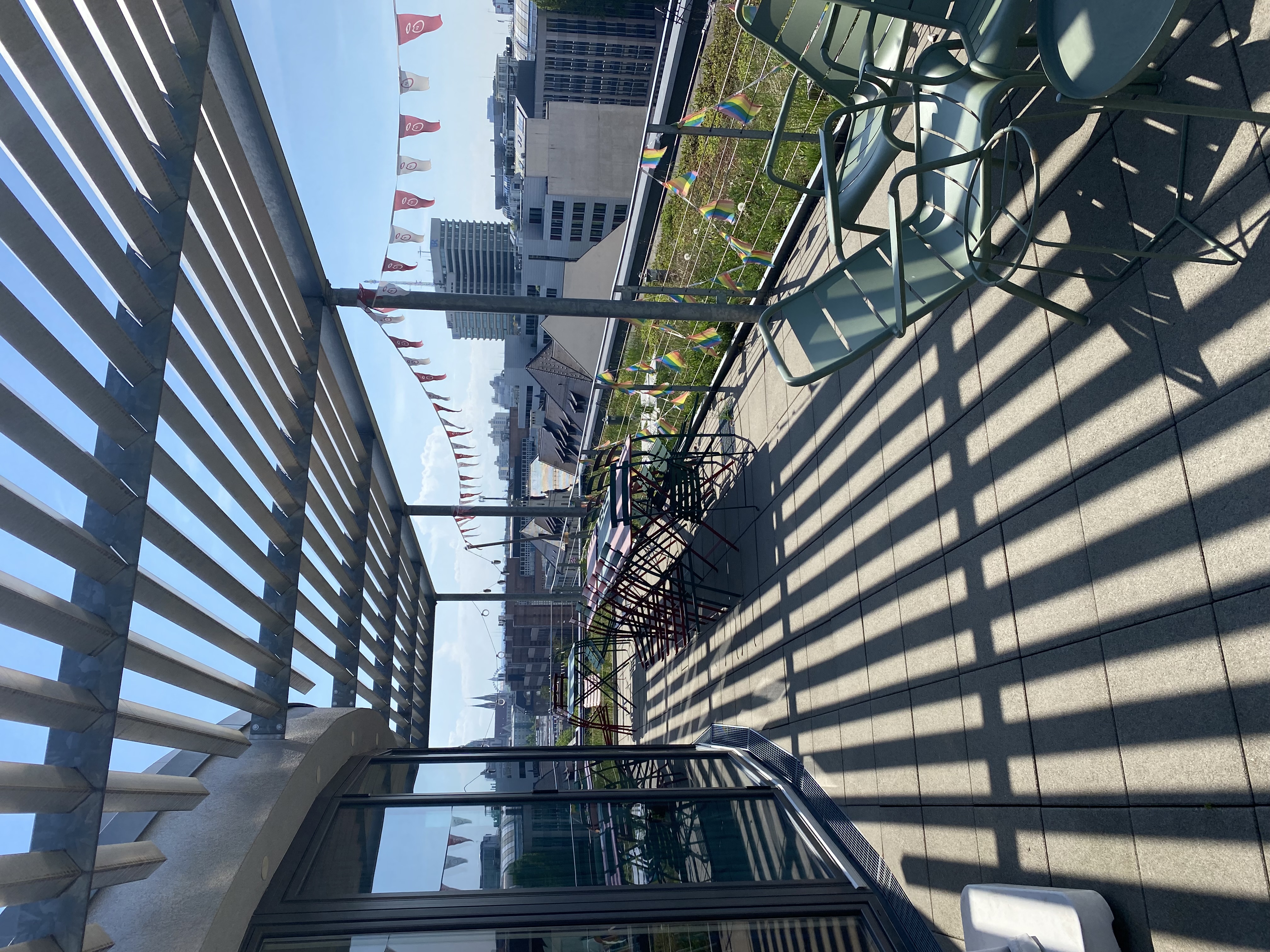 Rooftop with chairs, flags, and city view.