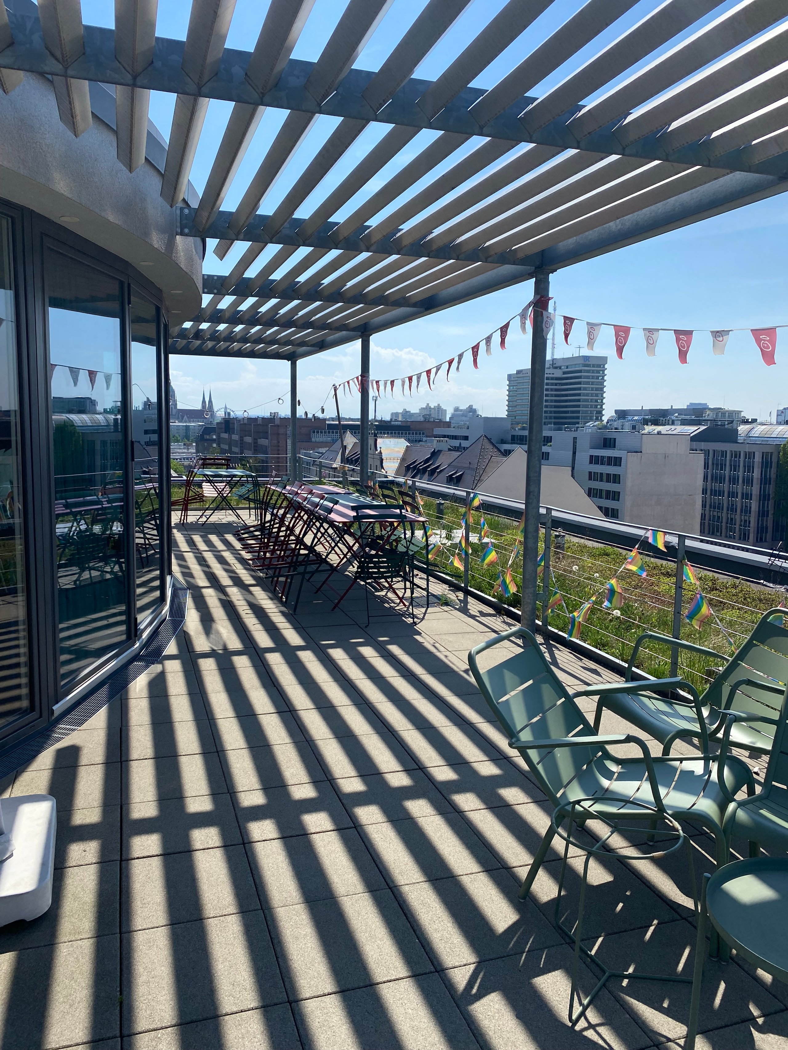 Rooftop with chairs, flags, and city view.