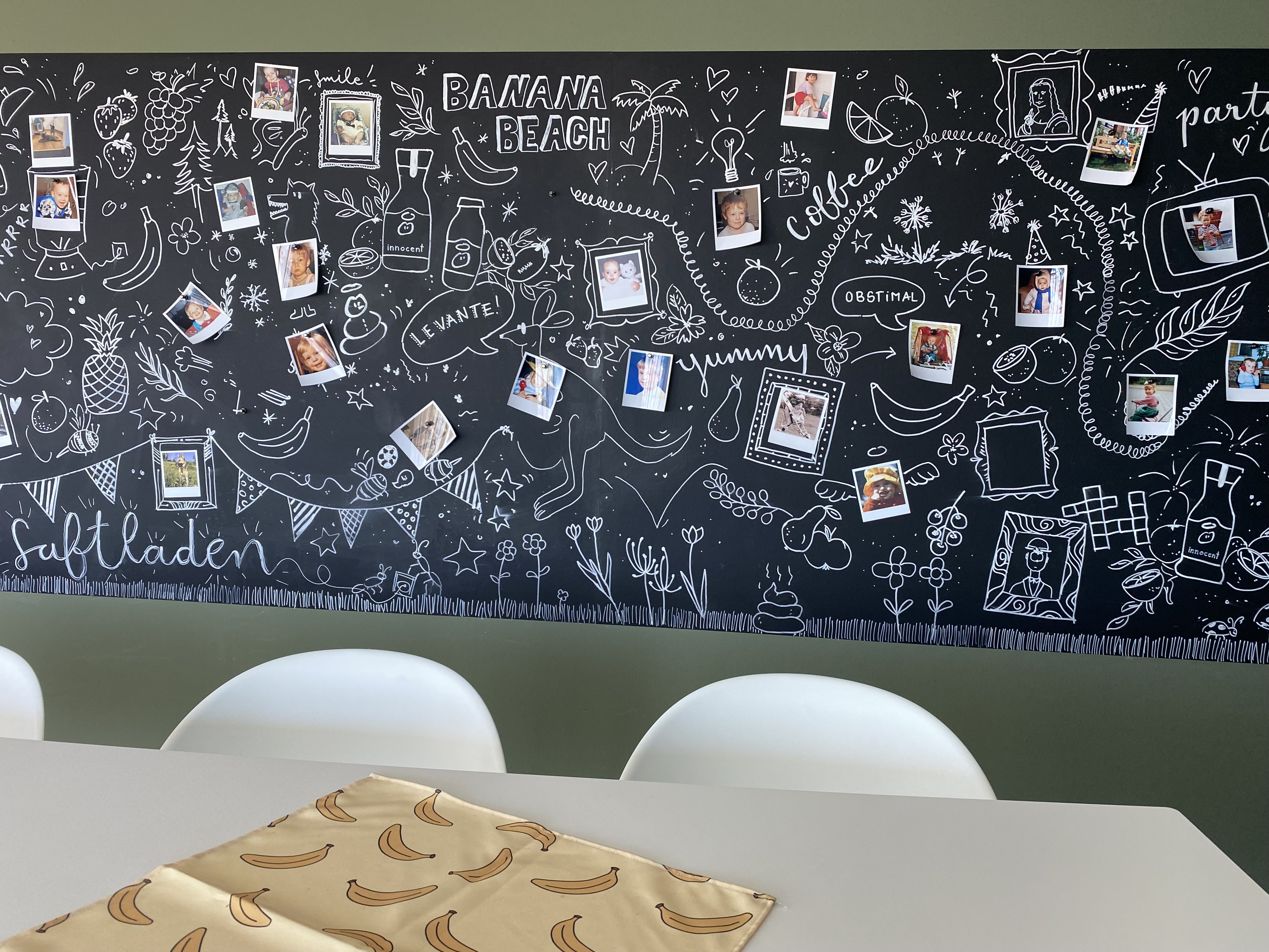 Blackboard with drawings and photos, table with banana pattern.