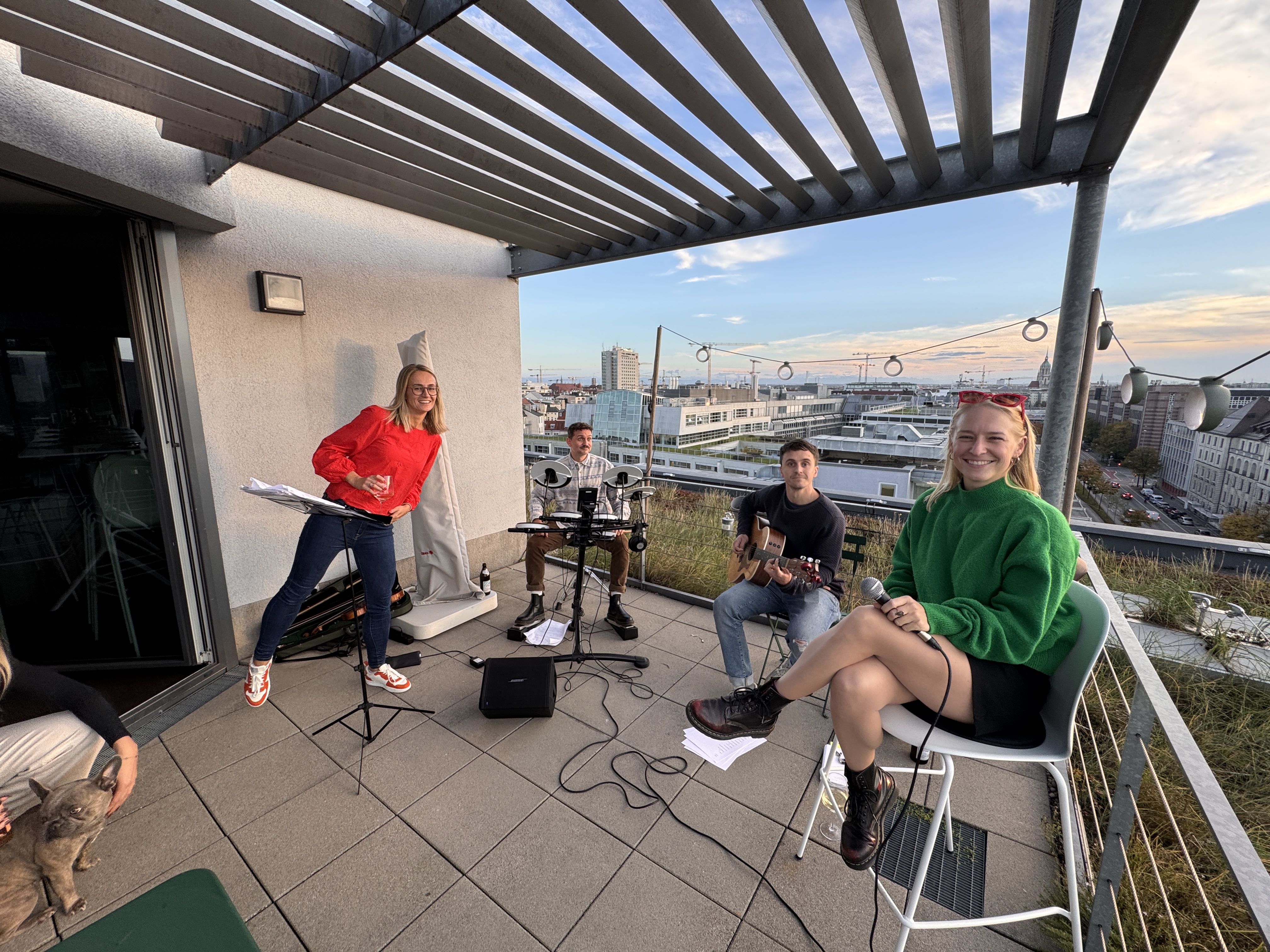 Group of people playing music on a rooftop with city views.