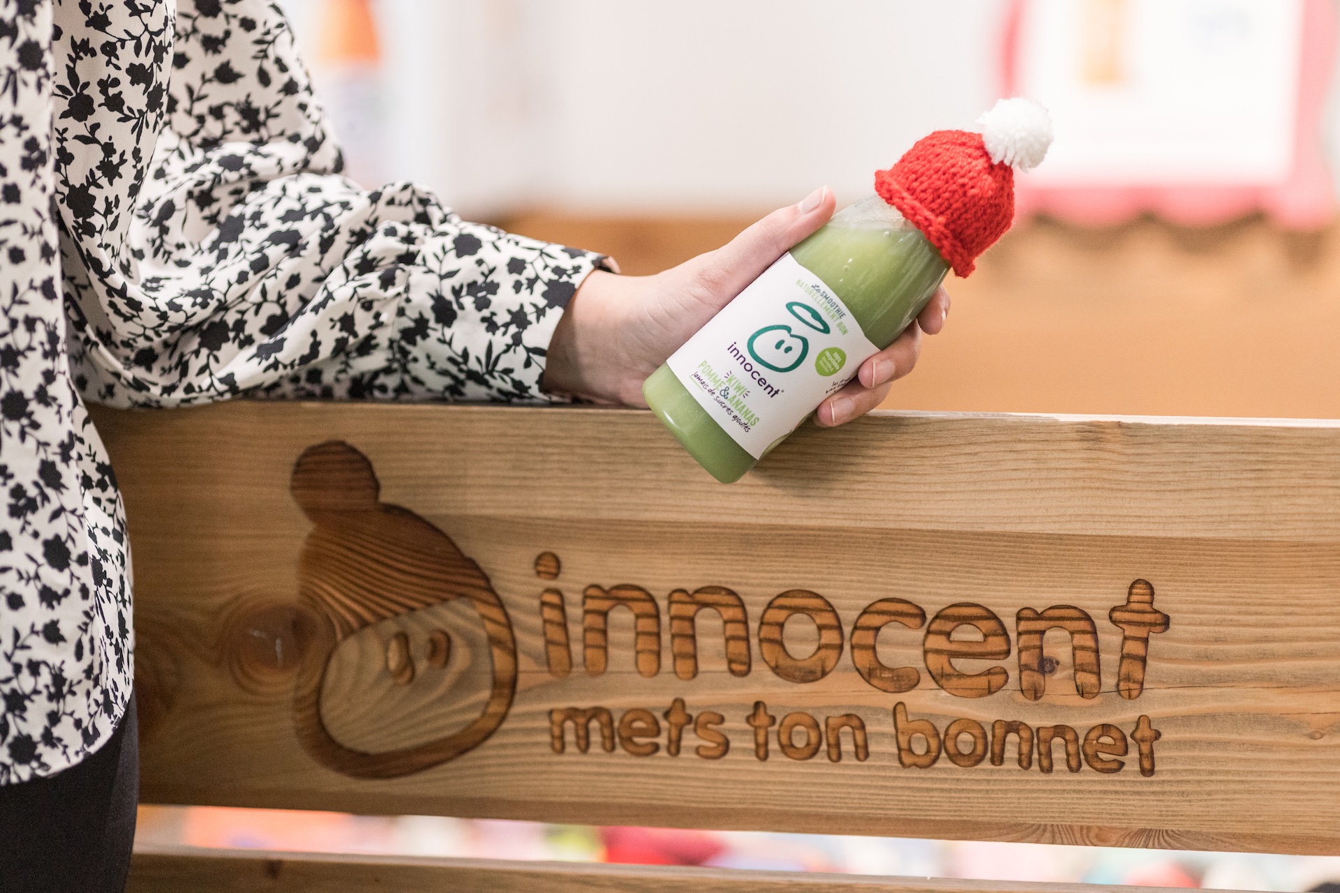 Person holding a bottle of Innocent smoothie with a small hat on it.