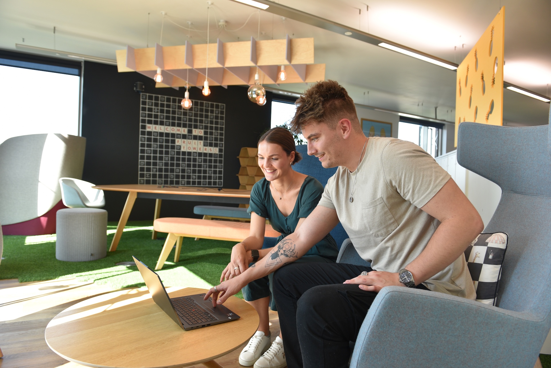 Man and woman looking at a laptop in a modern office setting.