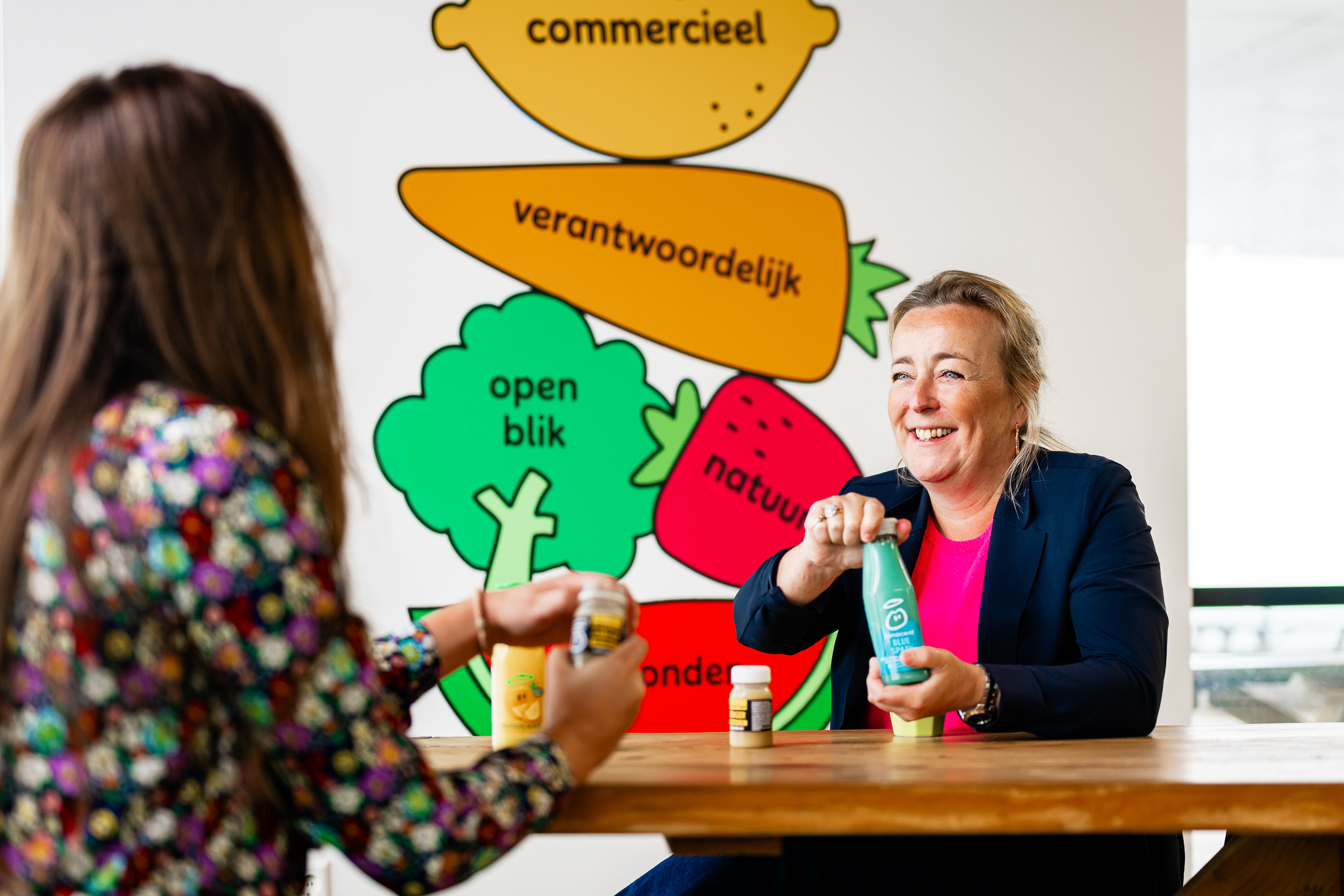 Two people with Innocent drinks bottles; colorful background.