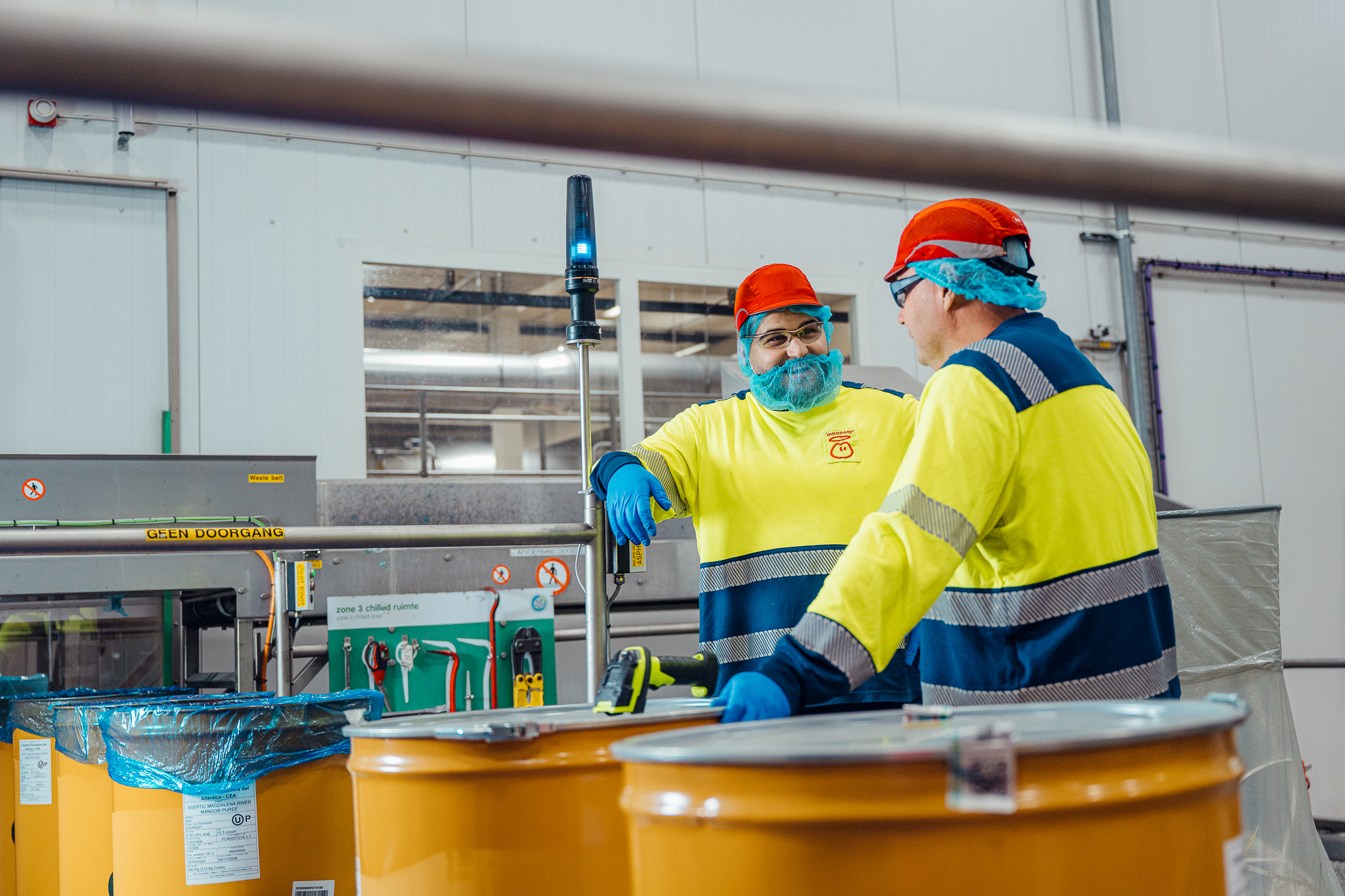 Two men in yellow uniforms working in a factory.