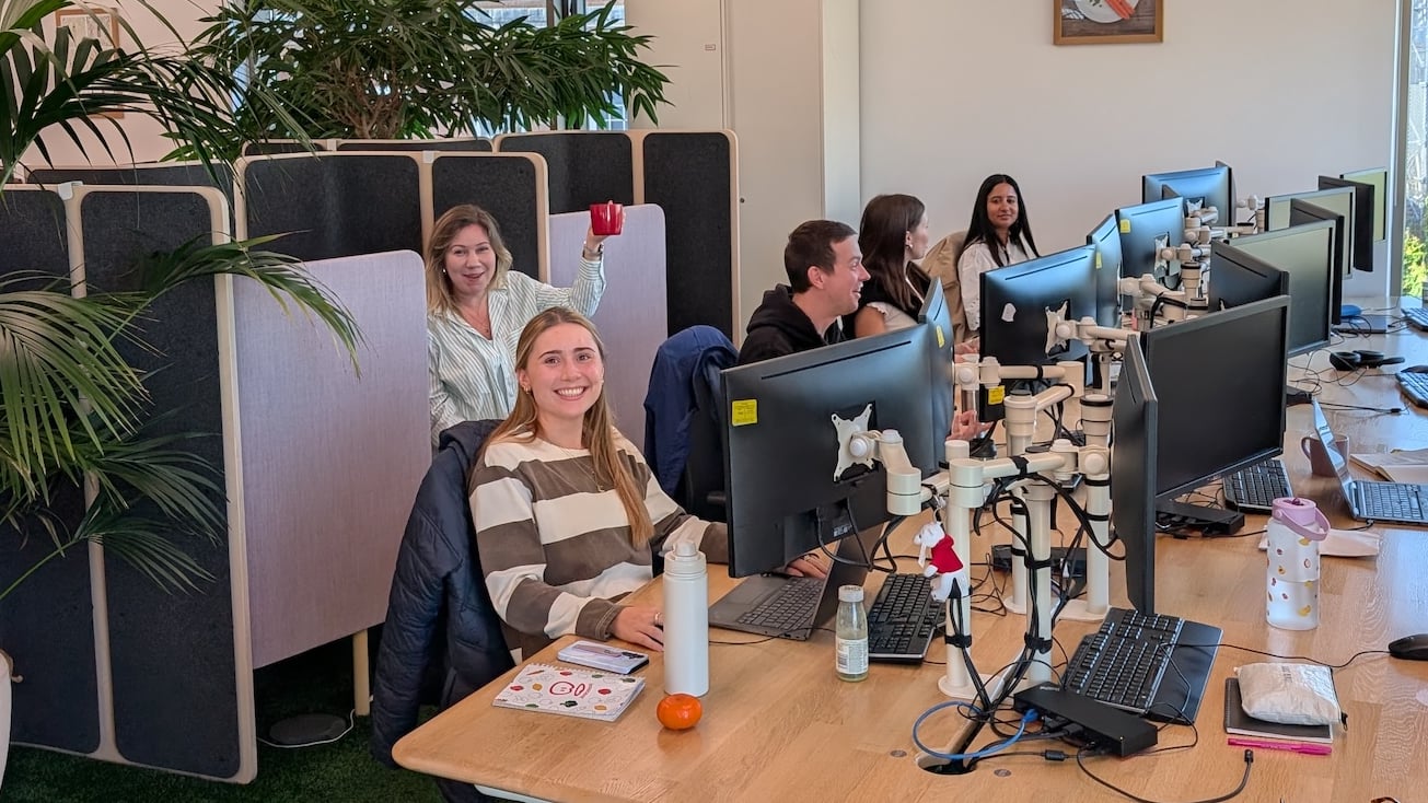 People at desks, plants, and computers in an office setting.
