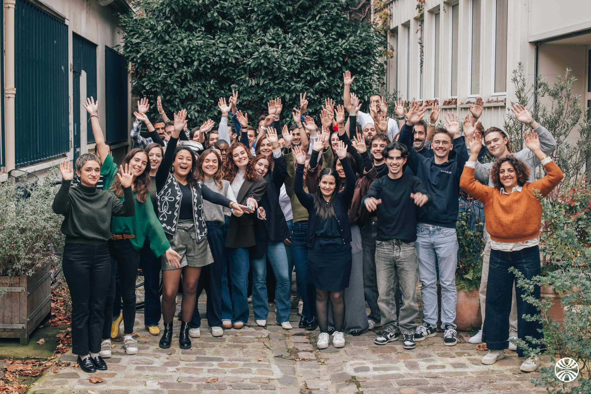 Group of people with raised hands, smiling and waving.
